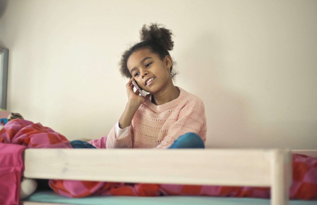 girl on bunk bed using mobile phone