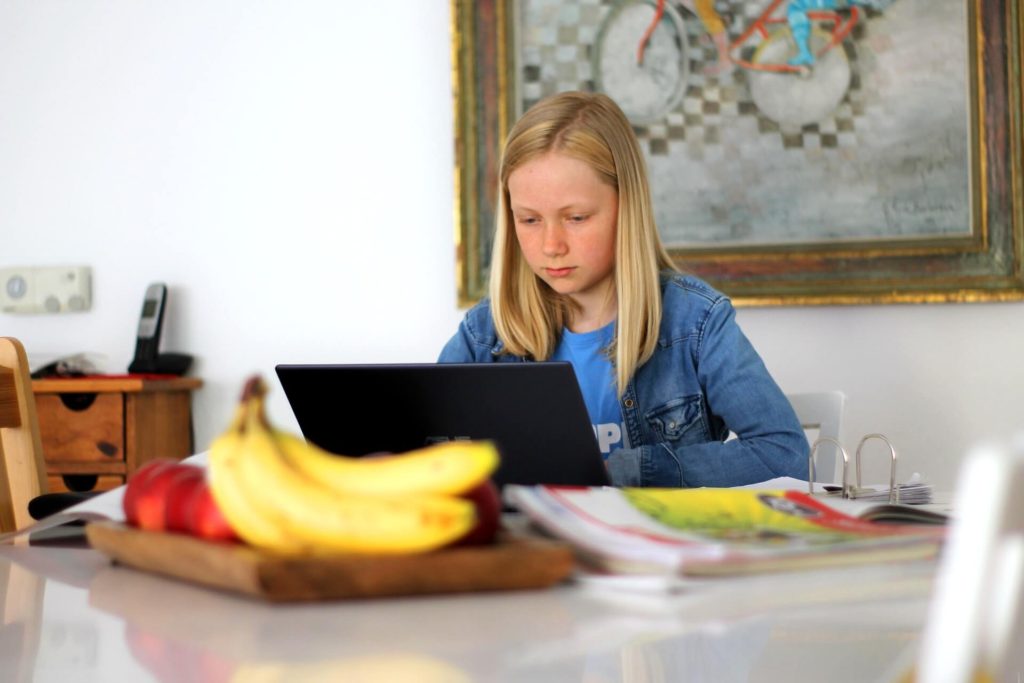 young girl working at laptop on dining table